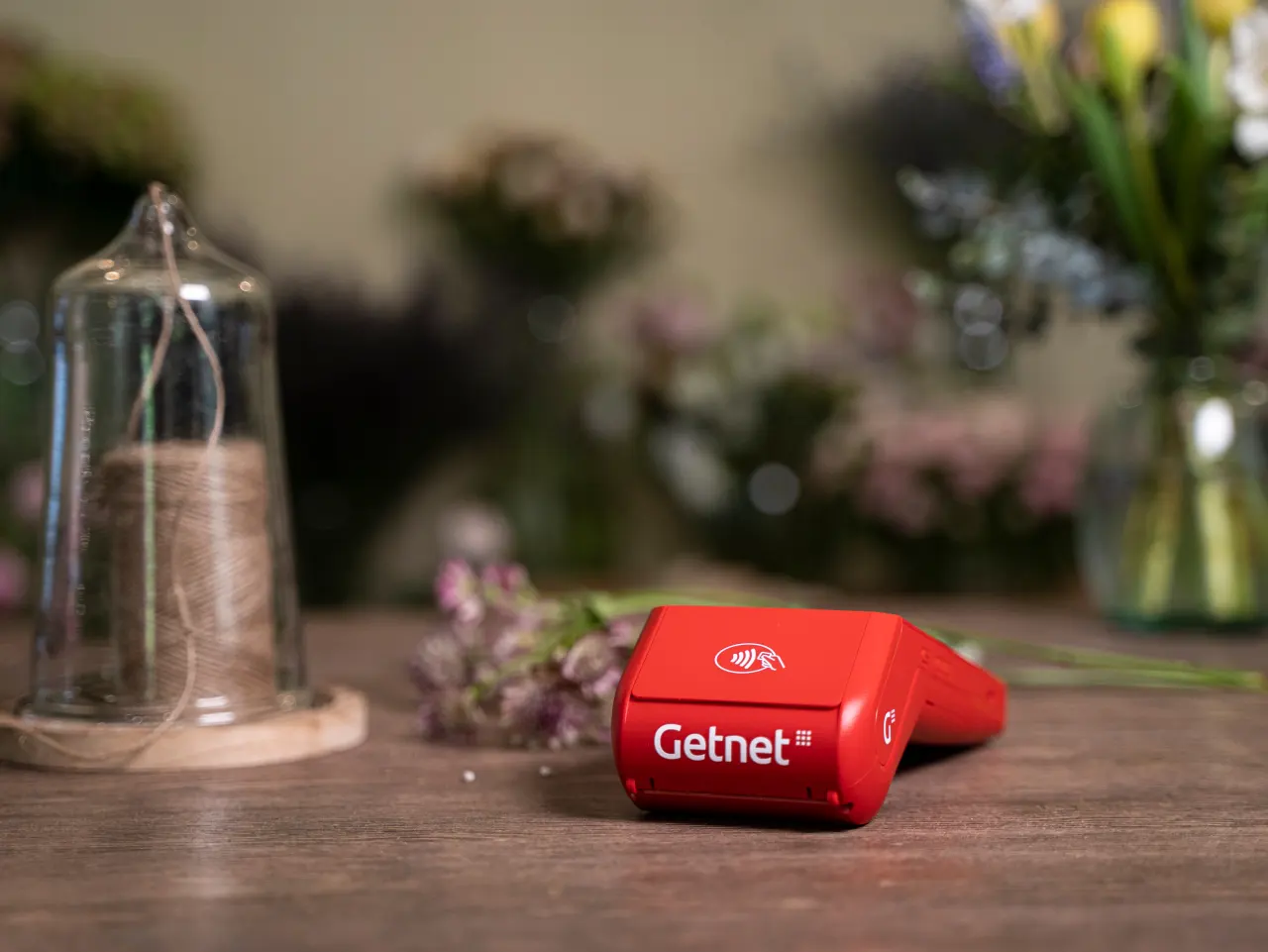 Mujer hablando por teléfono con un dispositivo Getnet en la mesa